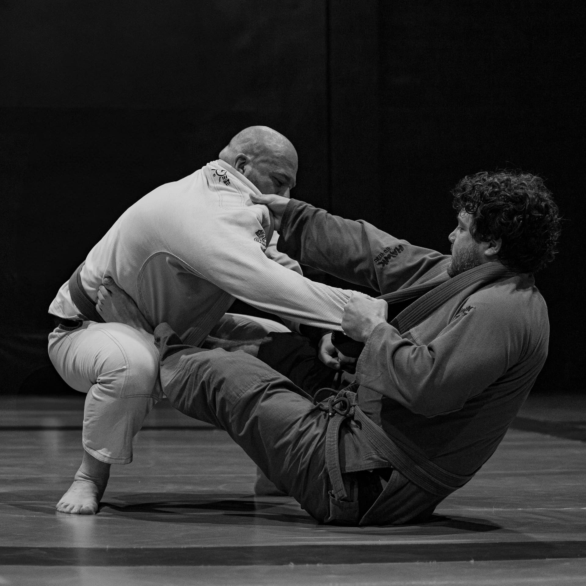 Two Brazilian jiu-jitsu athletes in the gi exchanging grips in open guard